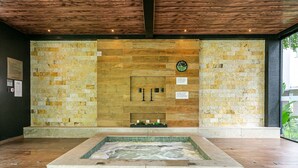 A spa area with a stone wall, a clock, and a hot tub. - Apartment in Thai Beach Home Spa Tbs1105 (Florianópolis)