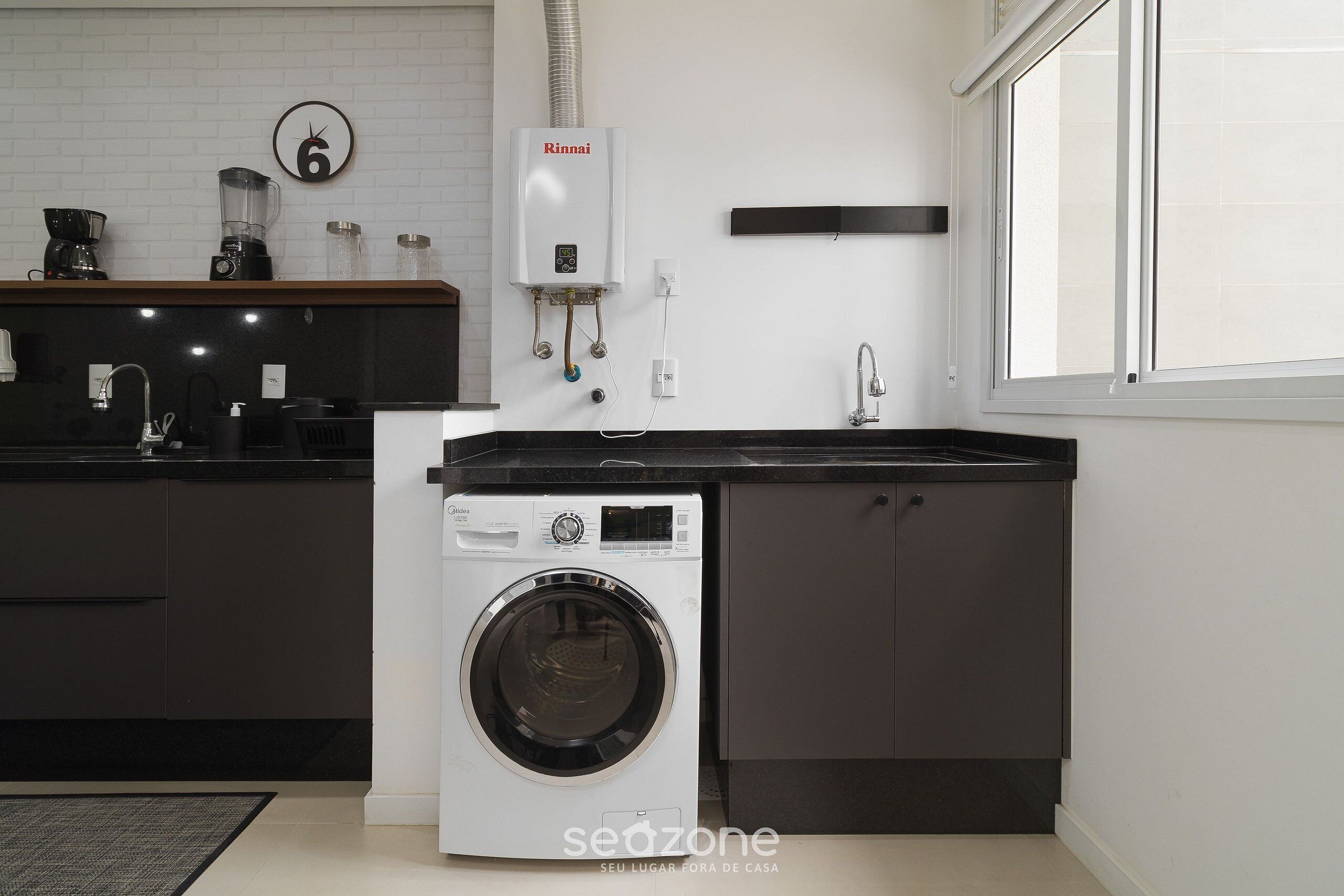 Eine moderne Küche mit integriertem Wasch- und Trockner, einer Kaffeemaschine und einer Wanduhr.