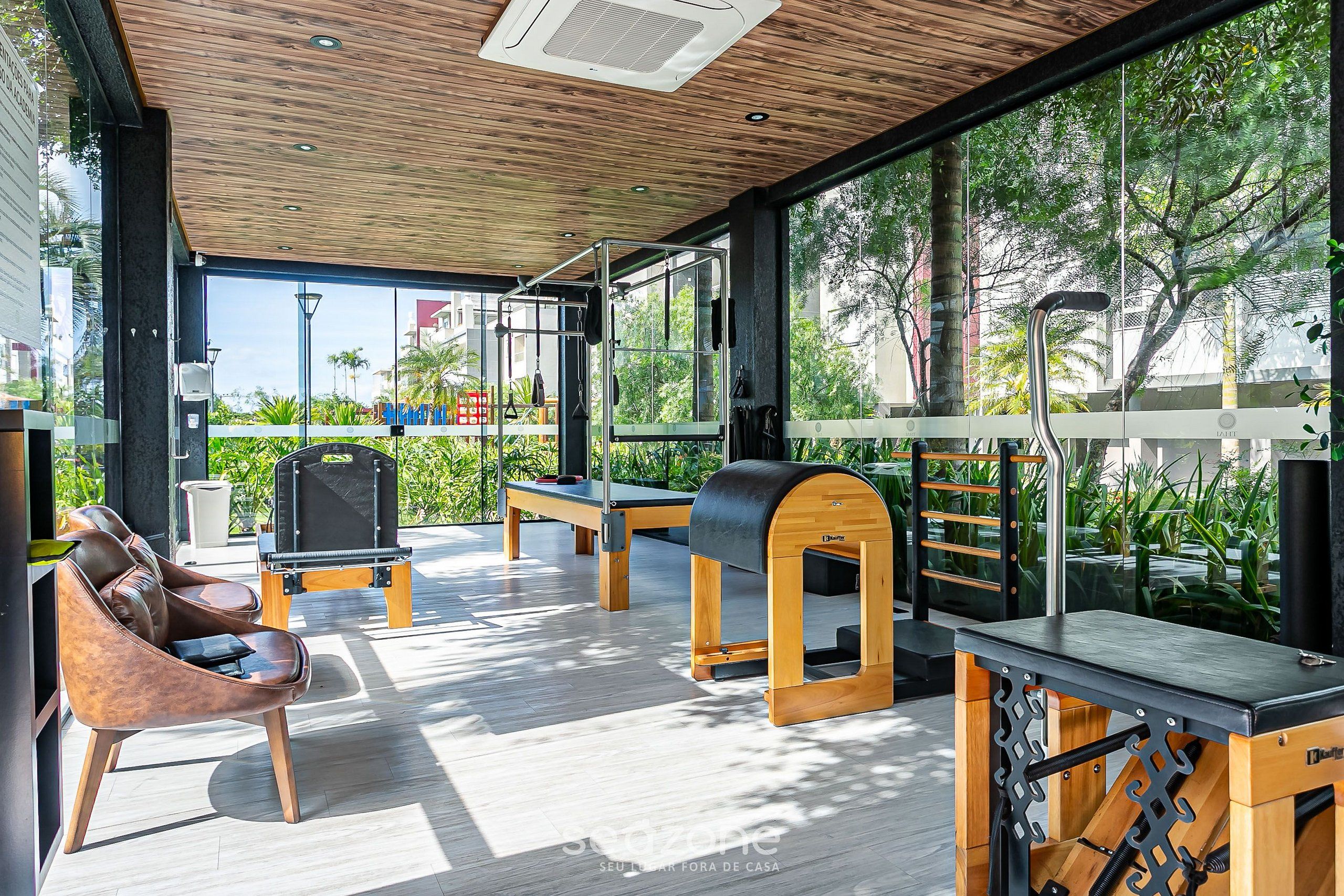 Un gimnasio al aire libre moderno con equipo de ejercicio, un banco de madera y una silla de lounge.