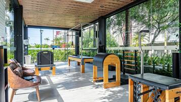 Un gimnasio al aire libre moderno con equipo de ejercicio, un banco de madera y una silla de lounge.