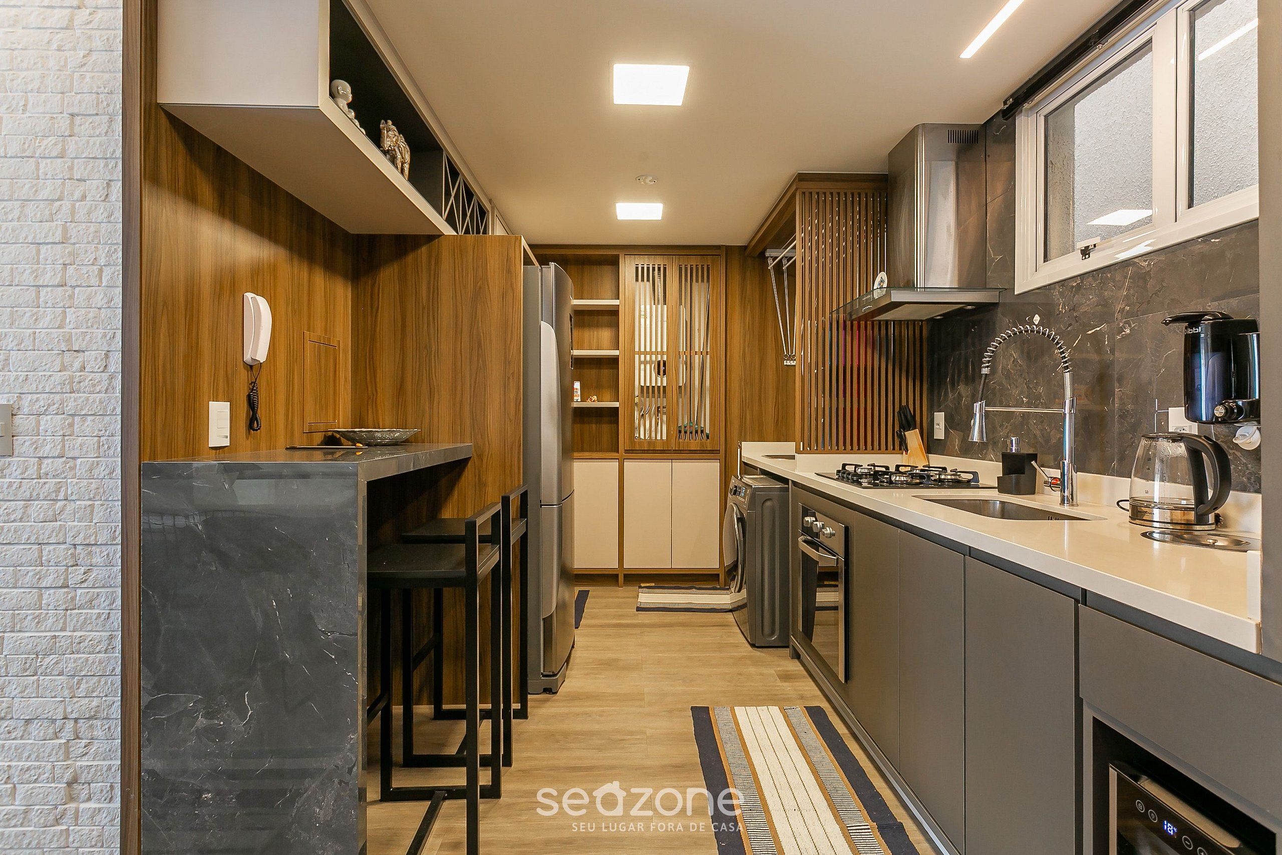 A modern kitchen with a built-in stove, a coffee maker, and a microwave. There is a wooden cabinet and a countertop.