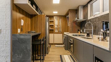 Una cocina moderna con estufa integrada, cafetera y microondas. Se observa un armario de madera y una encimera.