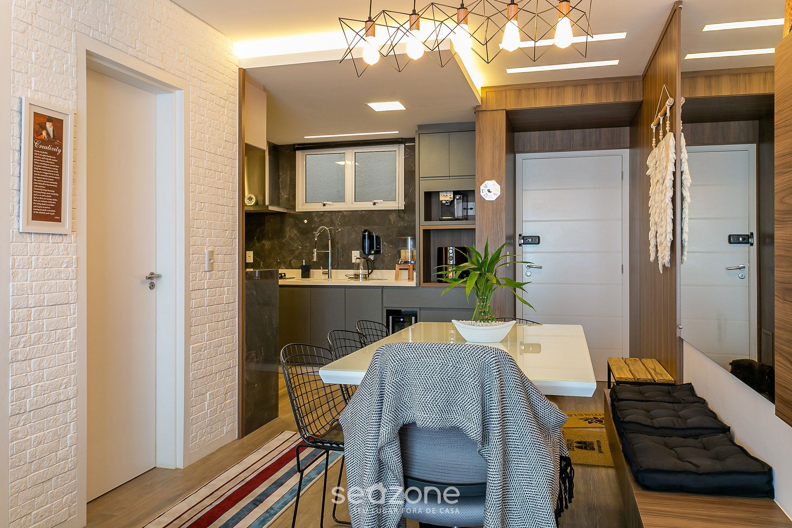 A modern kitchen with a dining area, a small seating space, and a visible door.