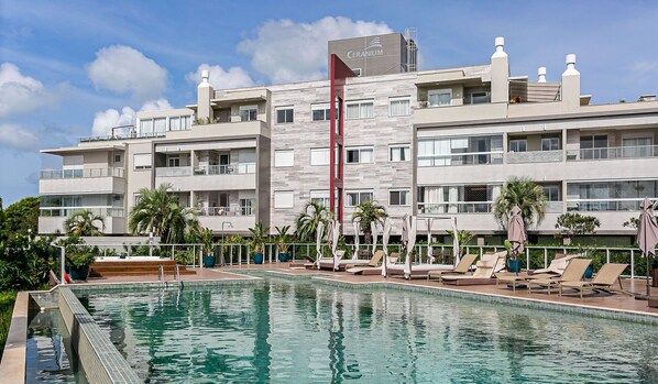 A hotel with a swimming pool, multiple balconies, and a modern architectural design. - Apart in Thai Beach Home Spa Cond sea Front Tbs106 (Florianópolis)