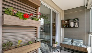 A balcony with wooden planters, a seating area with cushions, and a view of the cityscape. - Apart in Thai Beach Home Spa Cond sea Front Tbs106 (Florianópolis)