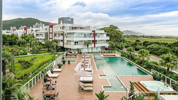 A hotel with a pool area, outdoor seating, and a view of the surrounding landscape. - Apart in Thai Beach Home Spa Cond sea Front Tbs106 (Florianópolis)