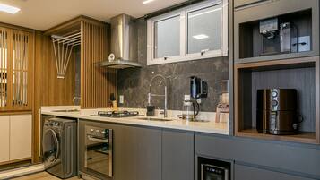 Una cocina moderna con electrodomésticos de acero inoxidable, horno empotrado, cafetera y una ventana sobre el fregadero.