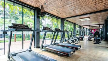 Un gimnasio con cintas de correr, máquinas de pesas y un amplio ventanal con vistas a zonas verdes.