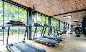 A gym with treadmills, weight machines, and a large window overlooking greenery. - Apart in Thai Beach Home Spa Cond sea Front Tbs106 (Florianópolis)