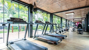 A gym with treadmills, weight machines, and a large window overlooking greenery. - Apart in Thai Beach Home Spa Cond sea Front Tbs106 (Florianópolis)