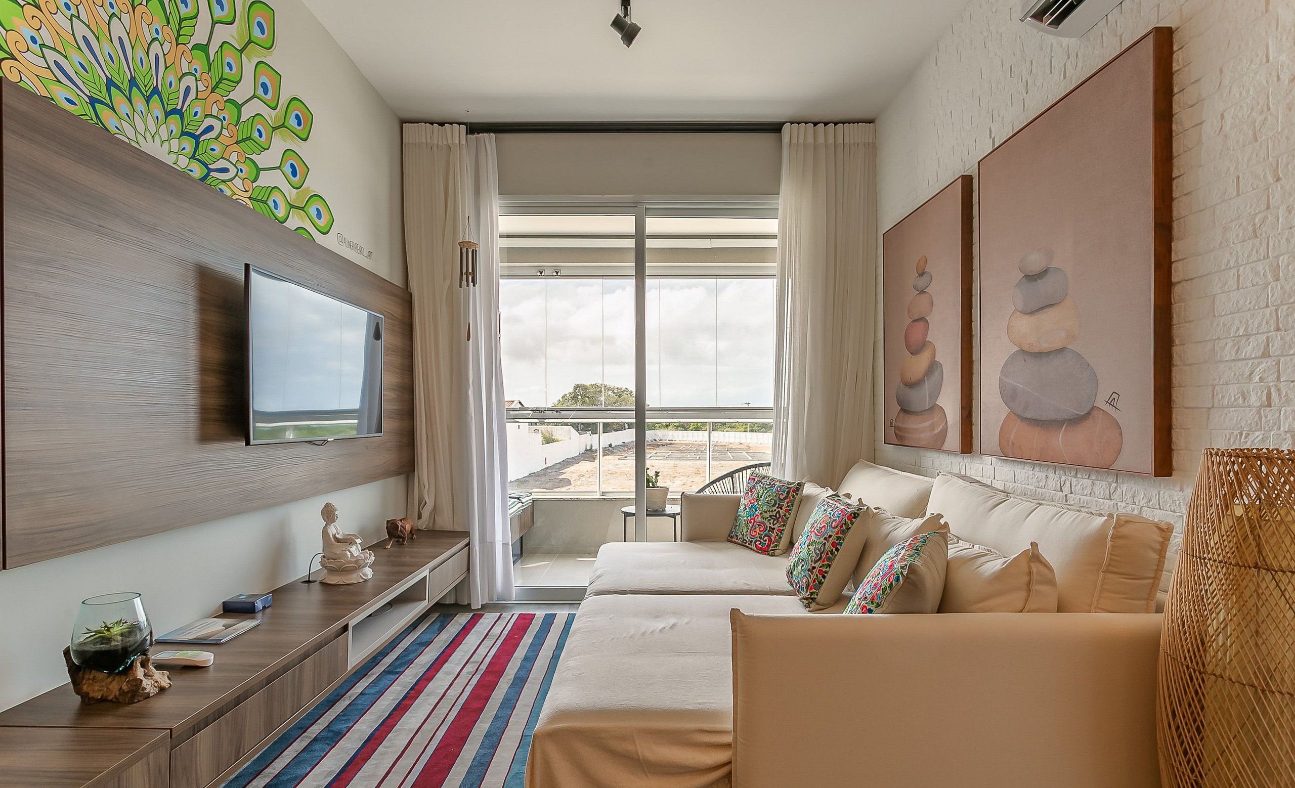 Una habitación de hotel moderna con una cama grande, un televisor montado en la pared, un balcón con vistas y obras de arte en las paredes.