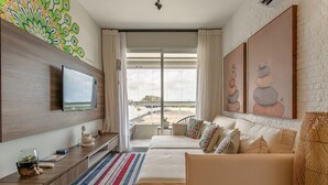 A modern hotel room with a large bed, a TV mounted on the wall, a balcony with a view, and artwork on the walls. - Apart in Thai Beach Home Spa Cond sea Front Tbs106 (Florianópolis)
