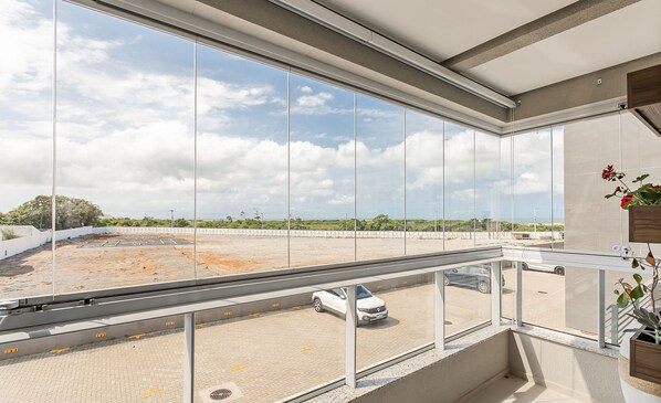 A balcony with a view of a parking lot and a clear sky. - Apart in Thai Beach Home Spa Cond sea Front Tbs106 (Florianópolis)