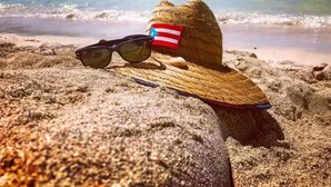 A straw hat and sunglasses on a sandy beach with a clear view of the ocean. - Aquatika Rent beach resort (Vieques)