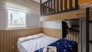 A bunk bed room with a city view, a window with blinds, and a television mounted on the wall.