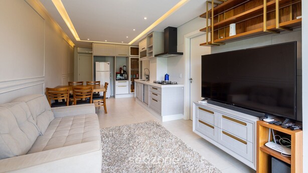 A modern living room with a sofa, TV, and kitchen area with cabinets and a TV stand.
