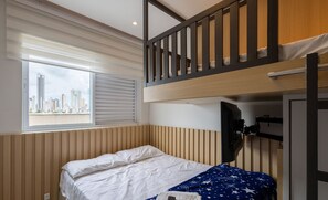 A bunk bed room with a city view, a window with blinds, and a television mounted on the wall. - 2BR Apt With BBQ Near the Beach - BC - Stl401 (Balneário Camboriú)