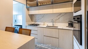 A modern kitchen with a marble countertop, stainless steel appliances, and wooden cabinetry. - Modern 2BR Apt Close to the Beach Stl0702 (Balneário Camboriú)