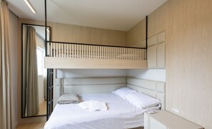 Un dormitorio moderno con una litera, un mesita de noche y un espejo grande.