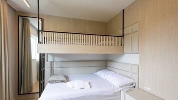 A modern bedroom with a bunk bed, a bedside cabinet, and a large mirror.