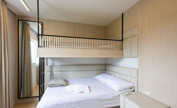 Un dormitorio moderno con una litera, un mesita de noche y un espejo grande.