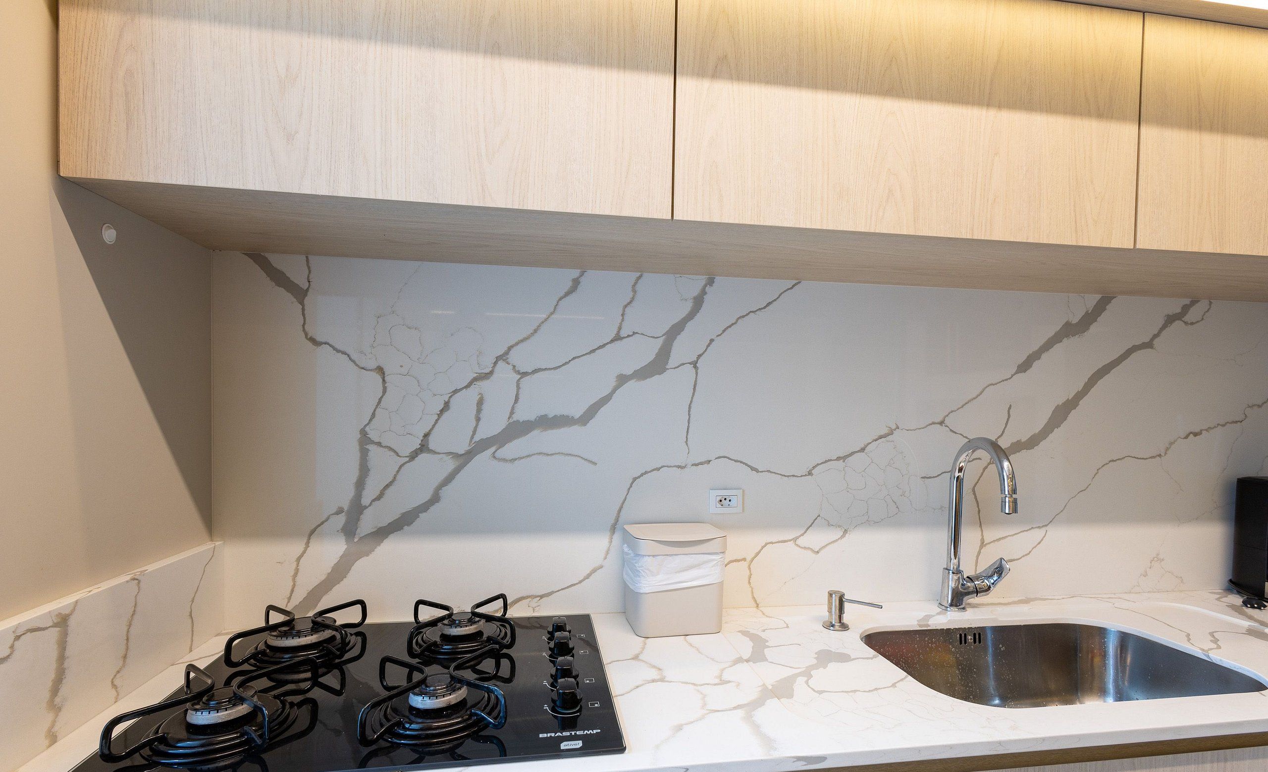 A modern kitchen with a gas stove, a sink, and marble backsplash.