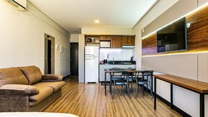 A modern kitchen with a built-in microwave, refrigerator, and wooden panel backsplash. - Studio in Condominium With Pool 700m Beach Sti210 (Florianópolis)