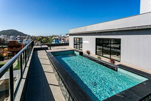 Una piscina en la azotea con vistas despejadas de la ciudad y una montaña al fondo.