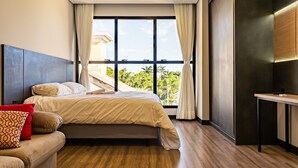 A modern hotel room with a large bed, a sofa, and a desk. The room has large windows with curtains, a view of greenery outside, and a wooden floor. - New Studio Well Located 750m From the Beach Sti209 (Florianópolis)