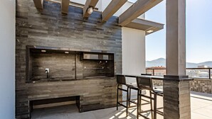 An outdoor kitchen area with a stone backsplash, a sink, and two bar stools. - New Studio Well Located 750m From the Beach Sti209 (Florianópolis)
