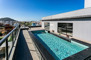 A rooftop swimming pool with a clear view of the city and a mountain in the background.
