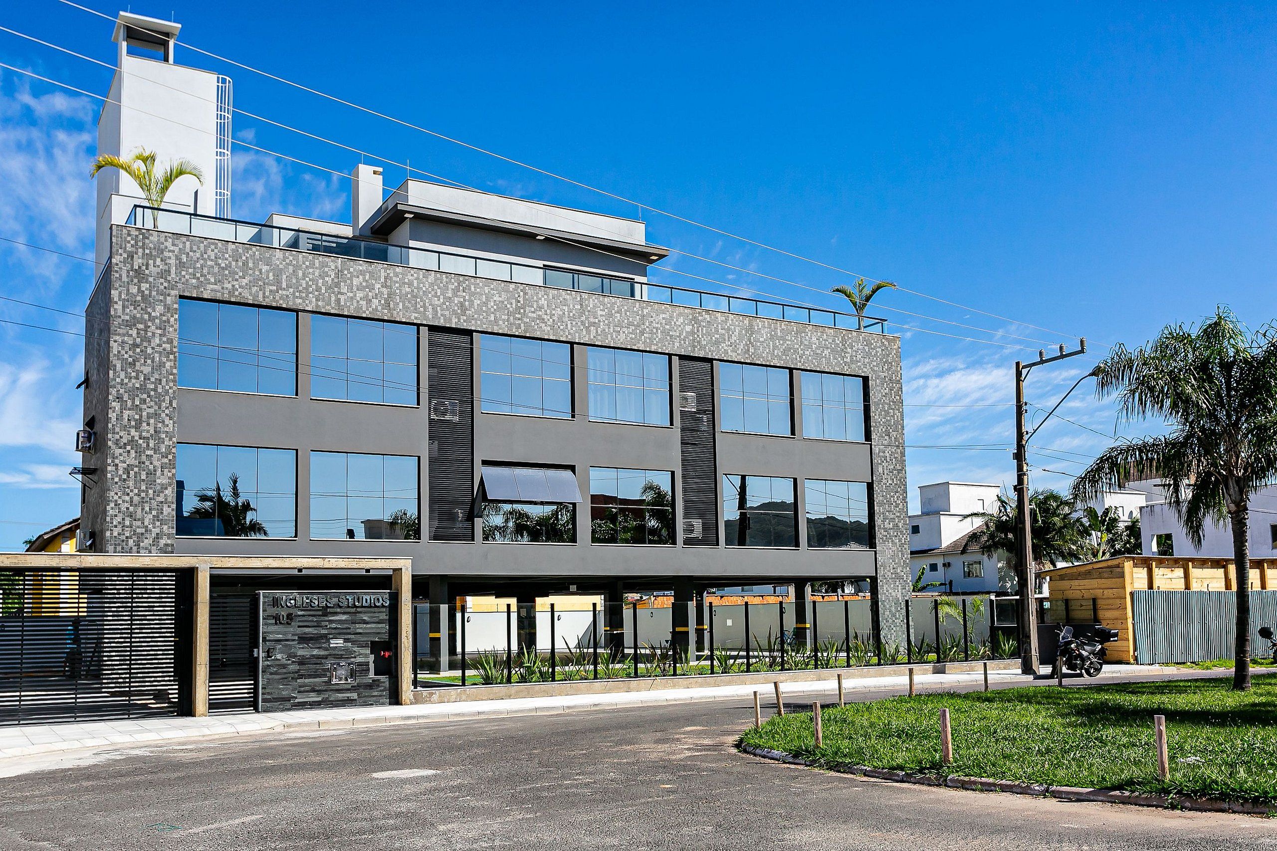 Um edifício moderno com estrutura em dois andares, grandes janelas e entrada coberta.