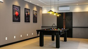 Una mesa de billar moderna en interior, con taco y rodeada de paredes en tonos neutros y decoración minimalista.