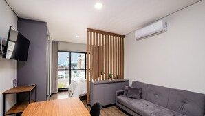 A modern room with a wooden table, grey sofa, and a TV mounted on the wall.