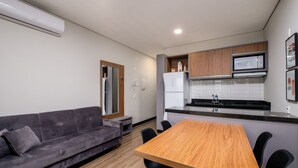 A modern kitchen with a wooden table and chairs, a grey sofa, and built-in appliances.