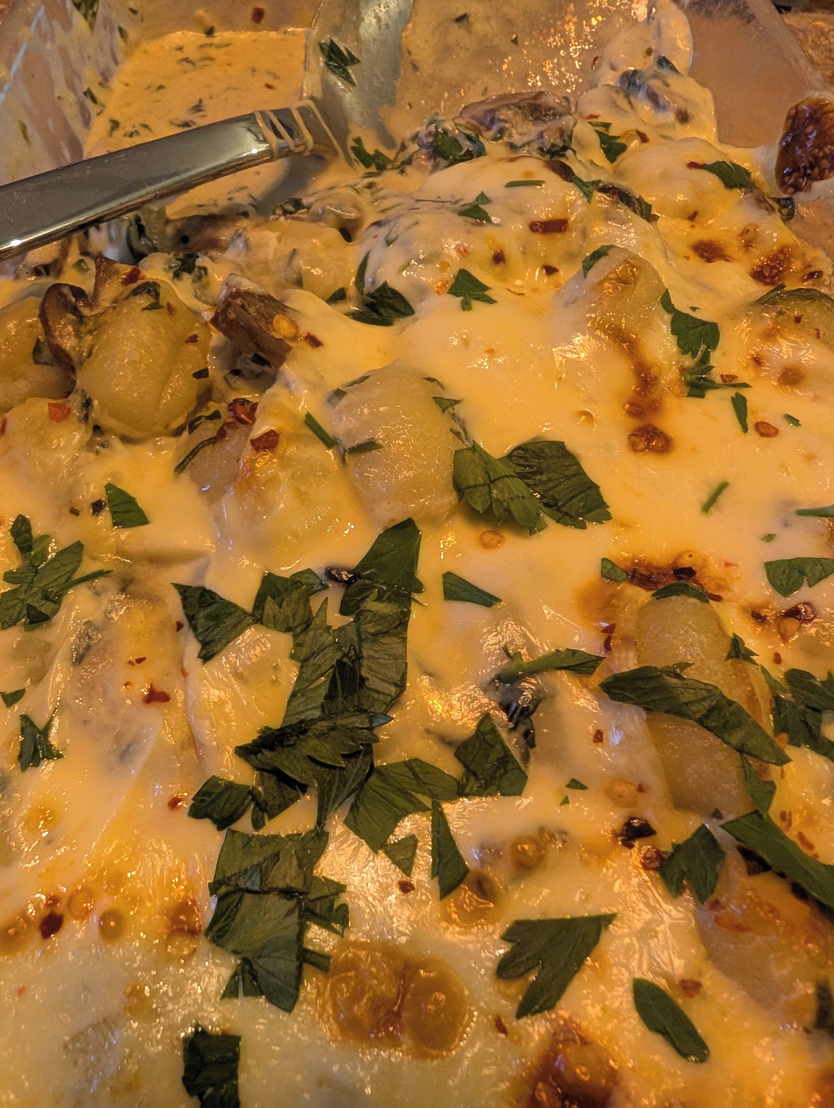 Primer plano de un plato cremoso con patatas y hierbas.