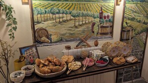 A dining area with a rustic wooden table set with pastries, fruits, and a wine bottle. - La Casa Della Seta  (Tremezzo)