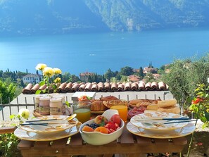 A breakfast table with a view of a lake and mountains. - La Casa Della Seta (Tremezzo)