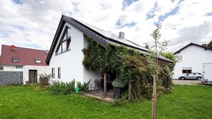 Una casa moderna con techo inclinado, un pequeño porche y un jardín.