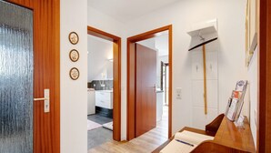 Un pasillo con una puerta de madera, un mostrador de recepción y una cocina al fondo.