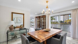 A dining area with a wooden table, grey chairs, a glass cabinet, and a chandelier.