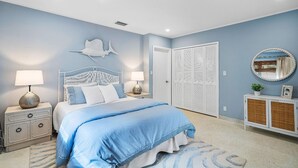 A bedroom with a bed, nightstands, a dresser, a wardrobe, and a mirror.