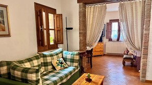 A cozy living room with a green plaid sofa, a wooden coffee table, and a stone pillar. - The Little House in the Courtyard, cozy vacation home with private courtyard in the center (Castelbuono)