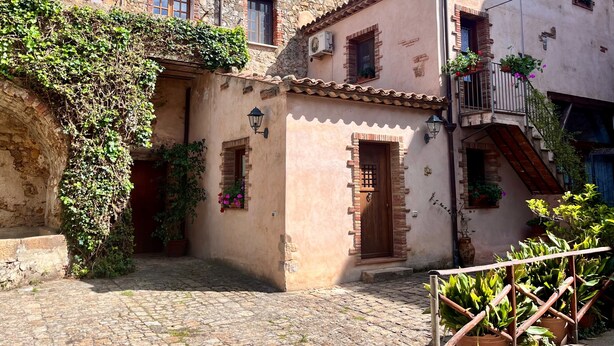 A traditional stone building with a cobblestone courtyard, wooden doors, and potted plants. - The Little House in the Courtyard, cozy vacation home with private courtyard in the center (Castelbuono)