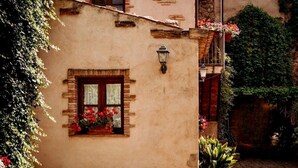 A building with a window with a flower box, a wall-mounted light, and a balcony with plants. - The Little House in the Courtyard, cozy vacation home with private courtyard in the center (Castelbuono)