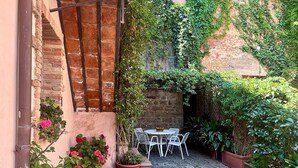 A cobblestone courtyard with a brick wall, a metal staircase, and potted plants. - The Little House in the Courtyard, cozy vacation home with private courtyard in the center (Castelbuono)