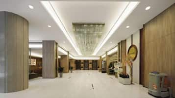 Um hall amplo com teto alto, iluminação embutida e um lustre central.