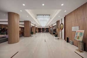 Een ruime lobby met een hoge plafond, gepolijste vloeren en houten details.