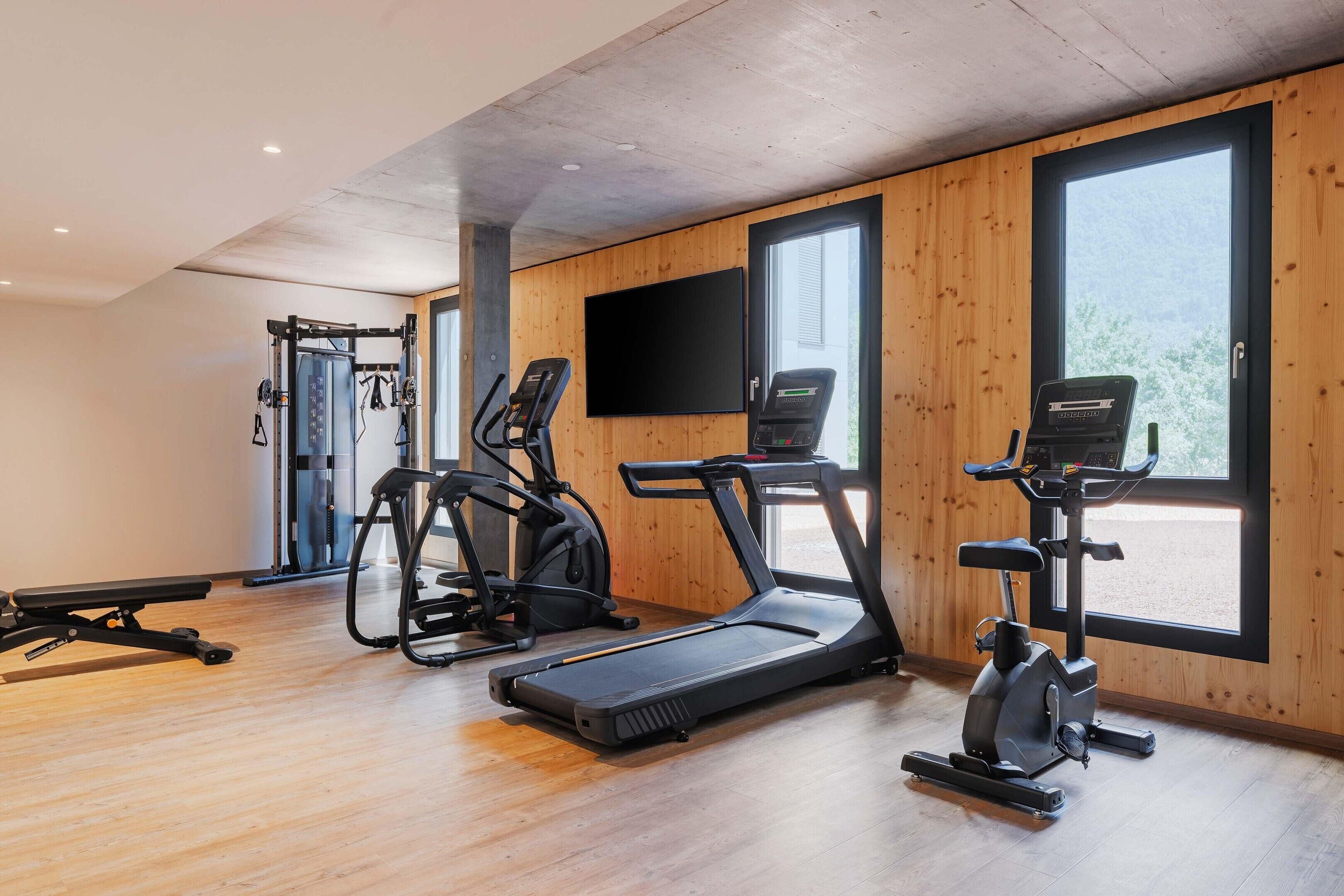 A gym with exercise equipment, large windows, and a wooden interior.
