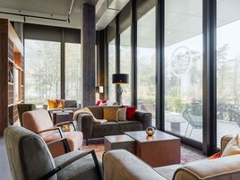 Una sala de estar moderna con ventanas amplias, chimenea y diferentes opciones de asientos.